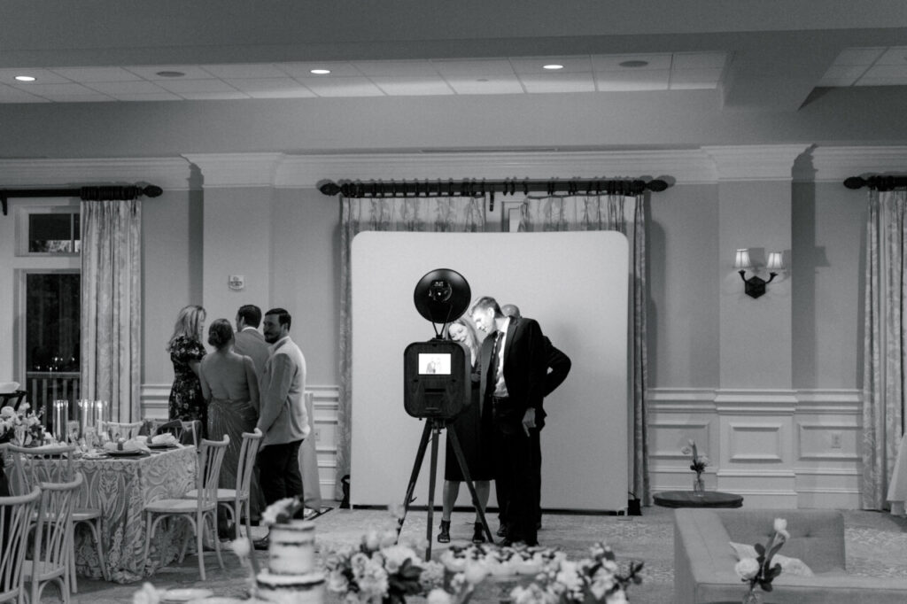 Guests utilizing a photobooth a wedding reception in front of a white background.