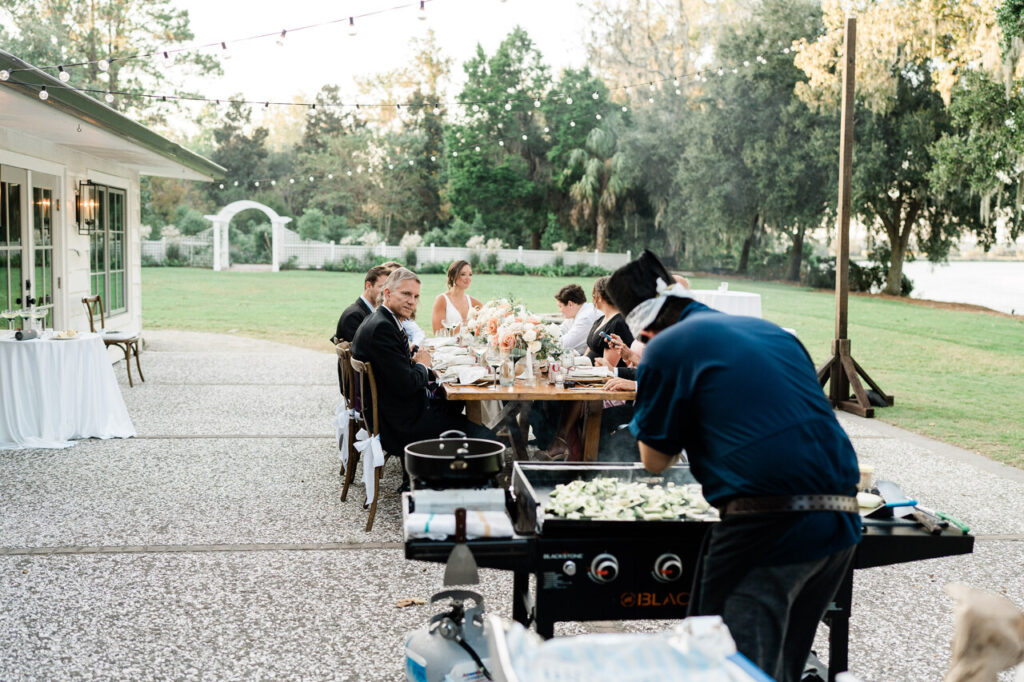 A hibachi chef cooking dinner on a blackstone griddle for an intimate small wedding on The Carriage House oyster tabby patio at Magnolia Plantation.