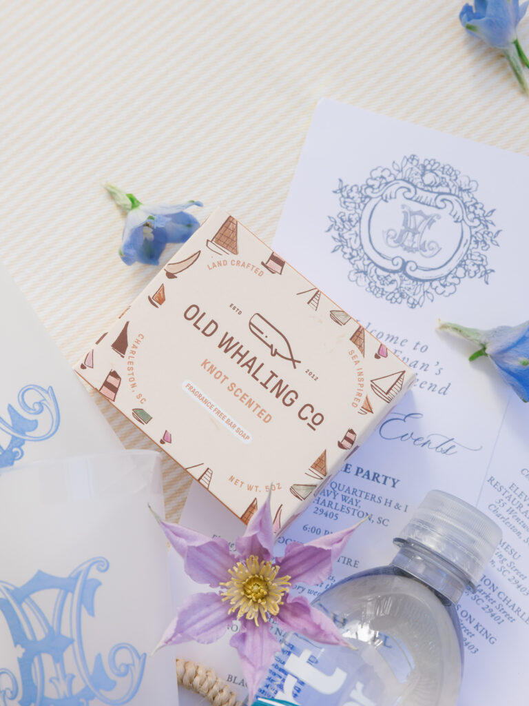 Surcies spilling out of a welcome bag for wedding guests at a welcome party featuring Old Whaling Company handmade soap made in Charleston, South Carolina along with an itinerary card for the wedding weekend.