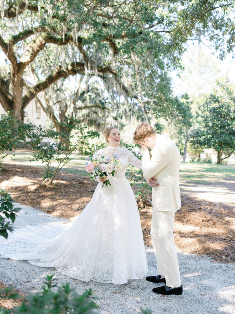 A bride and groom seeing each other for the first time on their wedding day with the bride holding her bouquet in a white wedding dress and the groom in an ivory suit.
