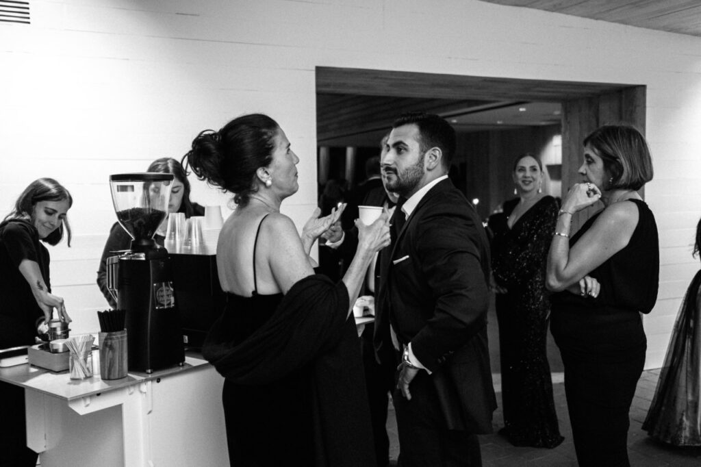Guests standing around a coffee cart a wedding reception sipping made-to-order cafecito.